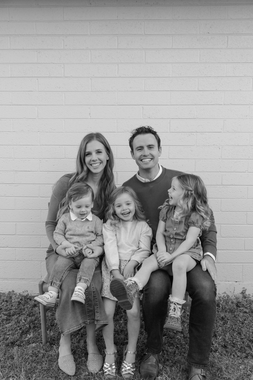 The Tucker family, two adults and three young children, seated together outdoors